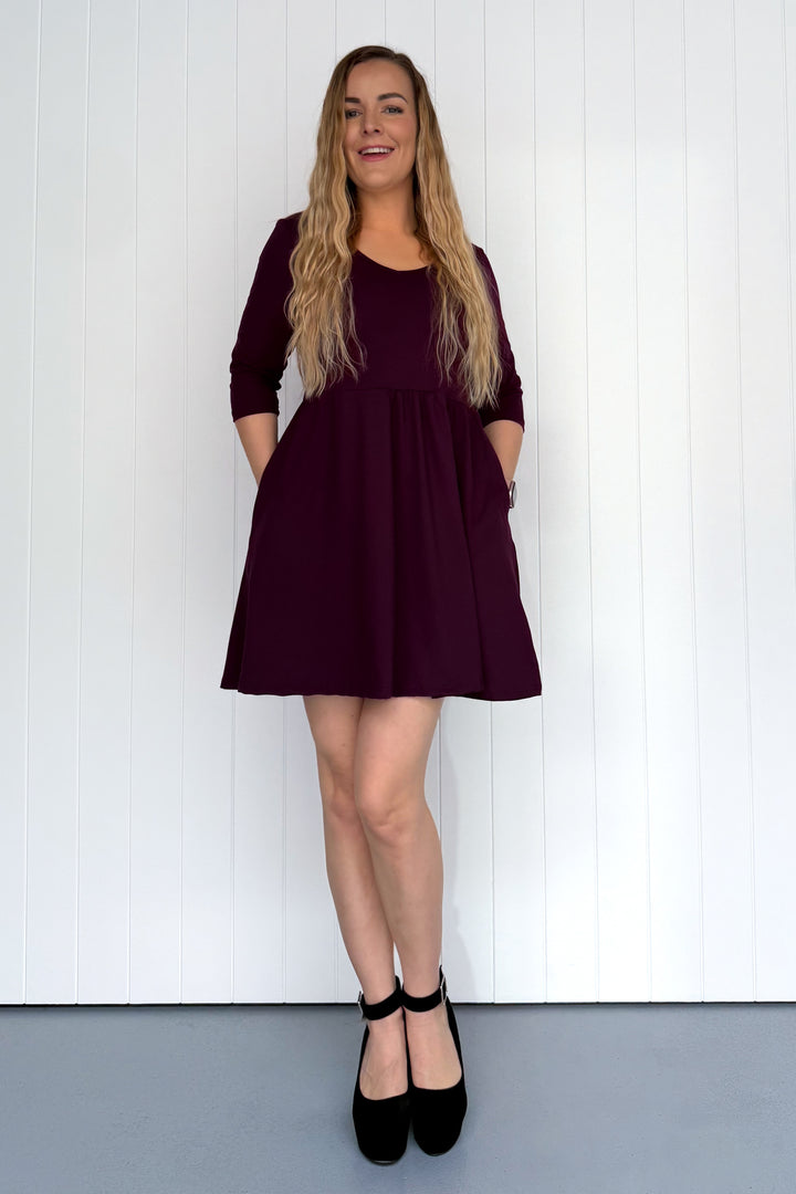 Woman wearing a burgundy dress standing against a white background