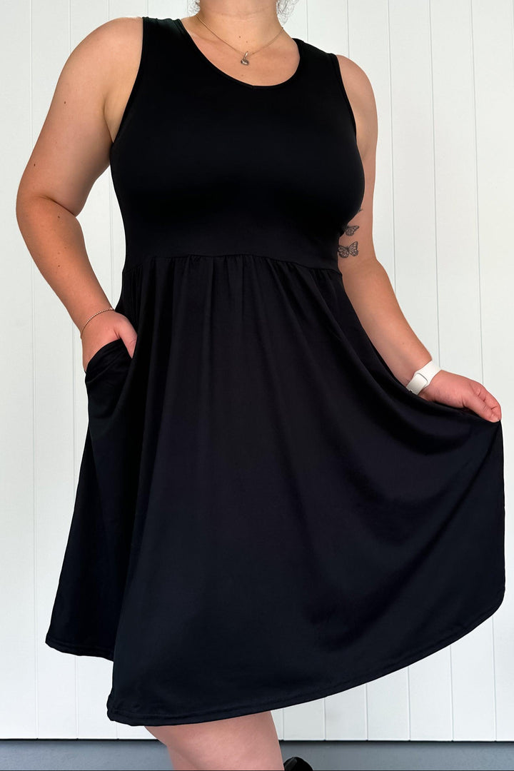 Person wearing a black sleeveless dress against a white background