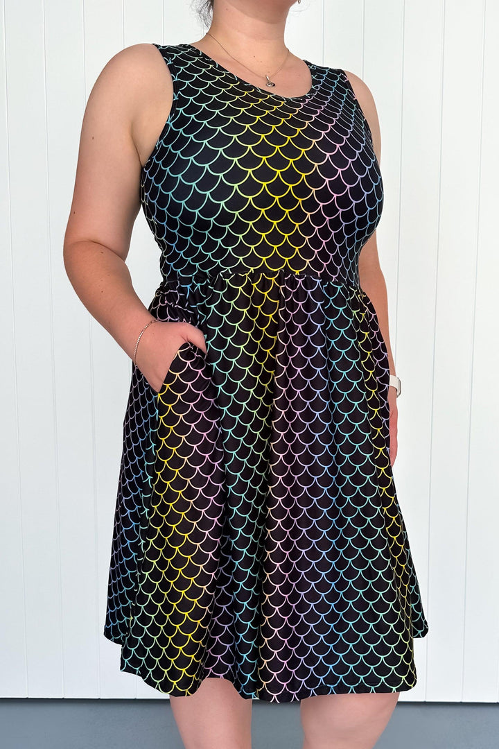 A sleeveless knee-length dress with a multicolored geometric pattern, featuring side pockets.