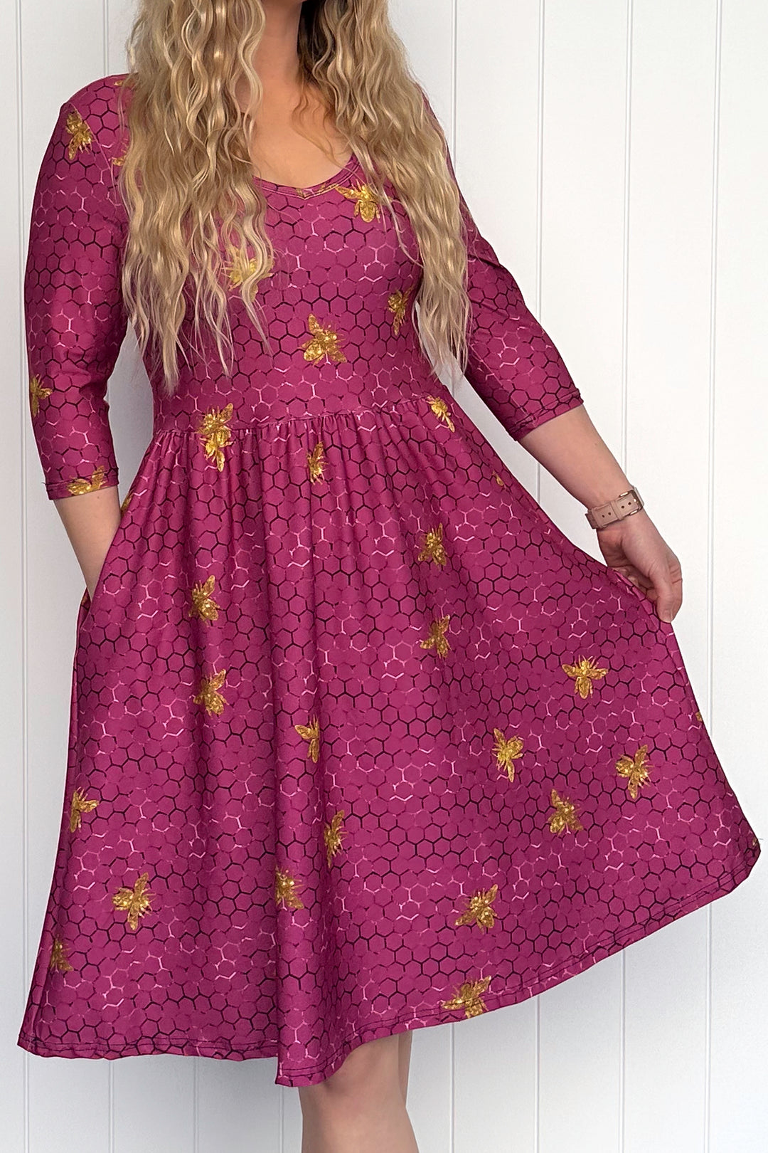 Woman wearing a maroon dress with bee patterns against a white background