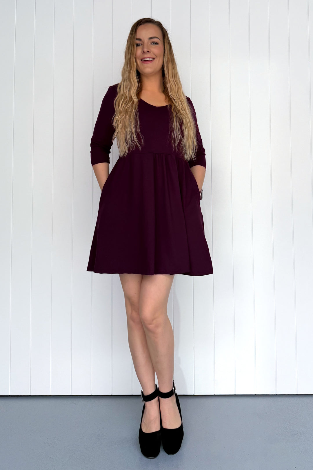 Woman wearing a burgundy dress standing against a white background