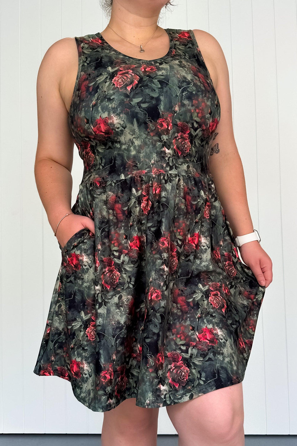 A sleeveless mini dress with a floral pattern featuring a rose motif, designed with a round neckline and side pockets.