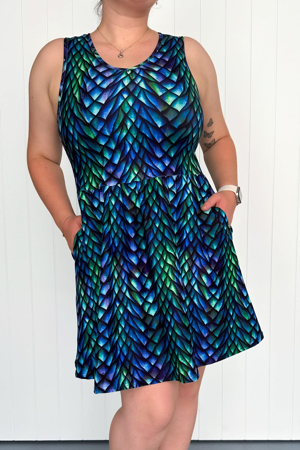 A sleeveless mini dress with a multicolored dragon scale pattern, featuring side pockets.
