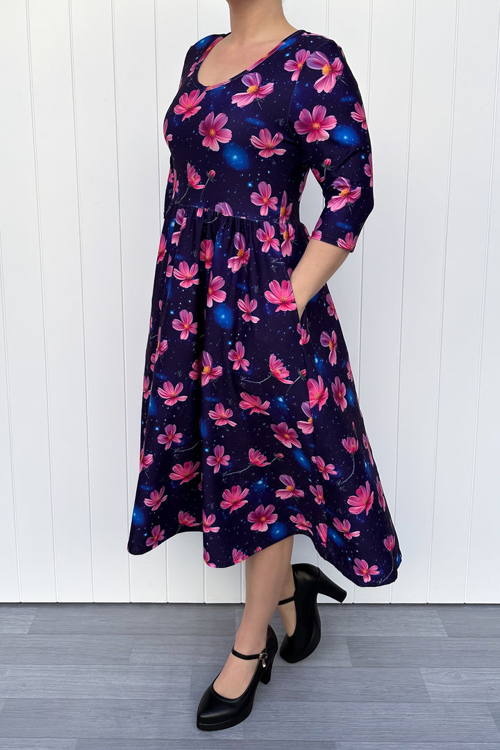 Woman wearing a floral dress with pink flowers on a navy galaxy background.