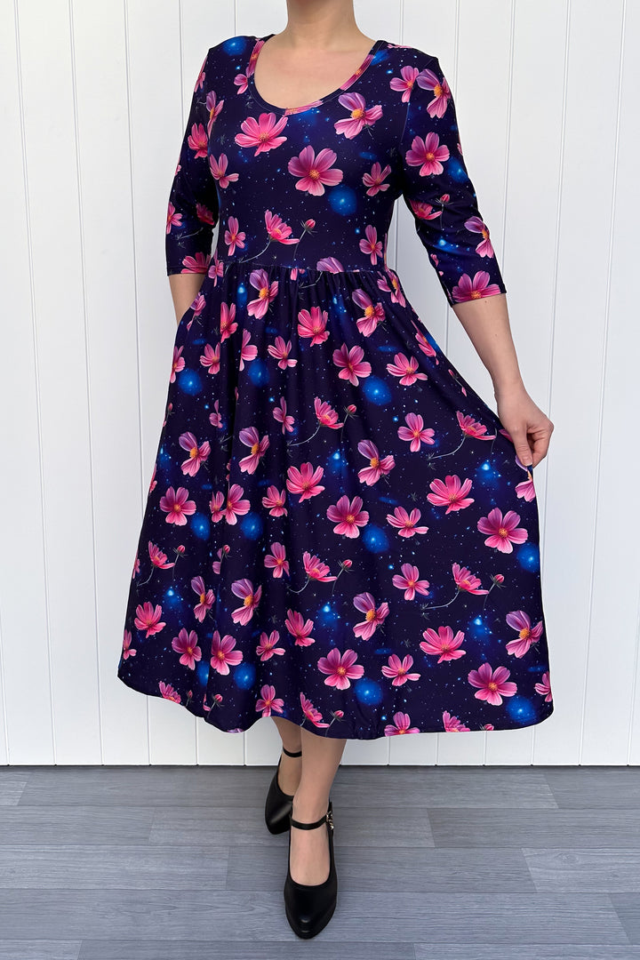 Woman wearing a floral dress with pink flowers on a navy galaxy background.