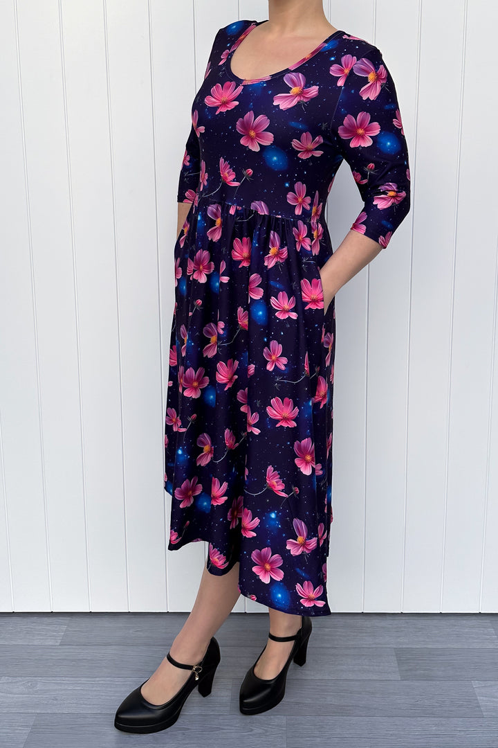 Woman wearing a floral dress with pink flowers on a navy galaxy background.