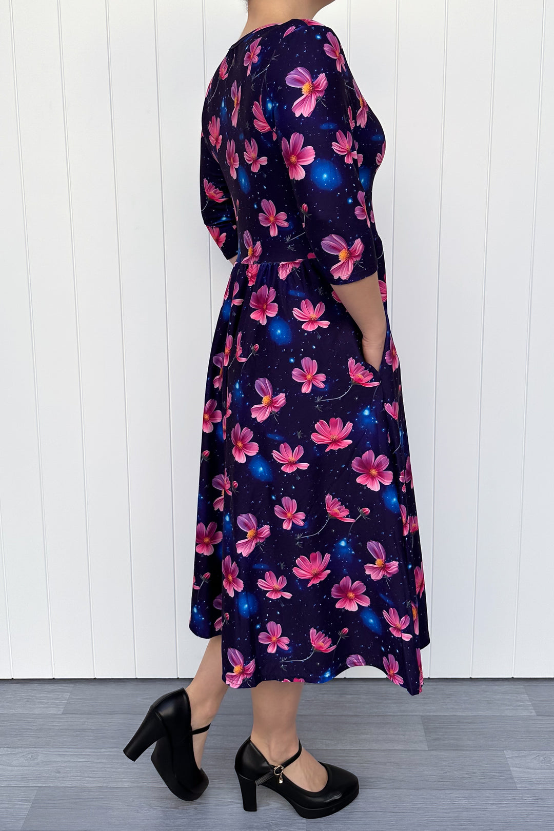 Woman wearing a floral dress with pink flowers on a navy galaxy background.