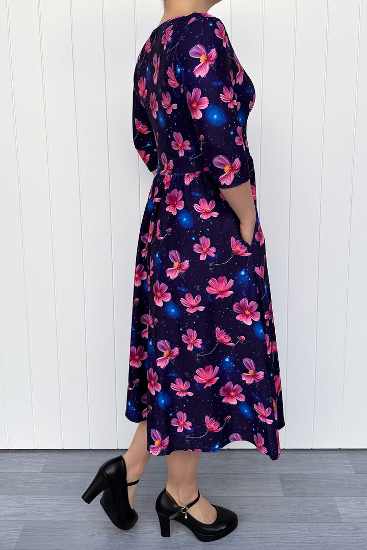 Woman wearing a floral dress with pink flowers on a navy galaxy background.
