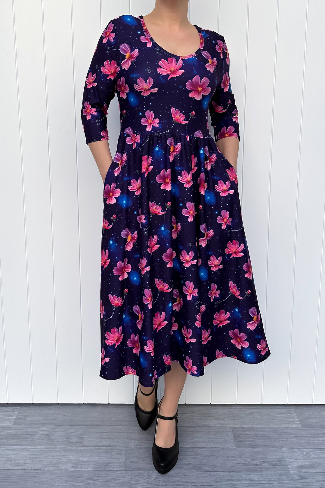 Woman wearing a floral dress with pink flowers on a navy galaxy background.