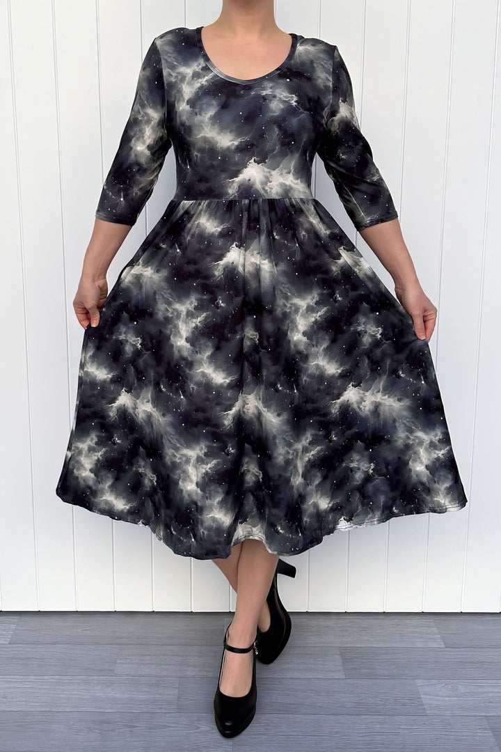 Person wearing a black and white patterned dress against a white wall.