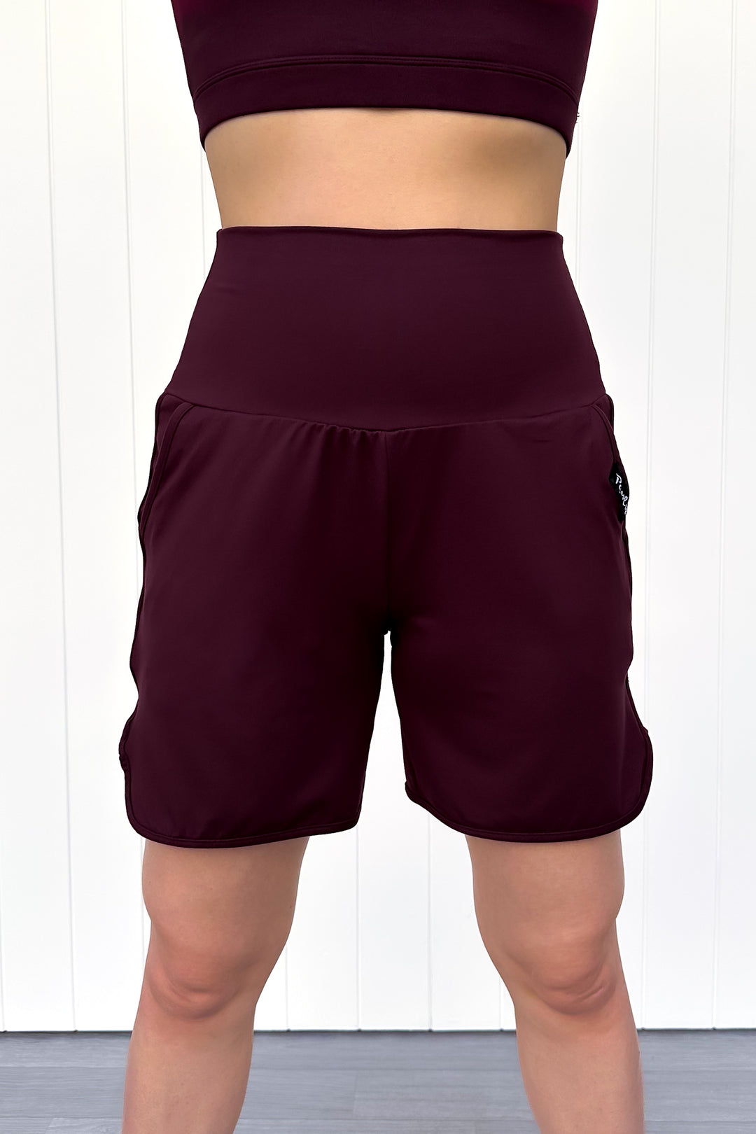 Maroon athletic shorts worn by a person on a white background