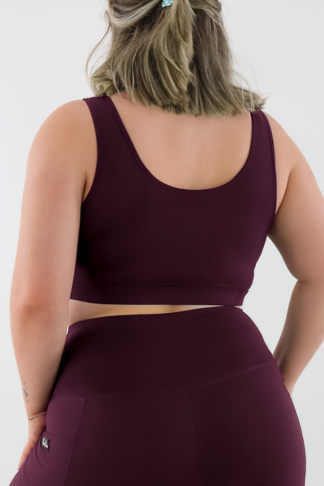 Person wearing a maroon sports bra and leggings on a white background