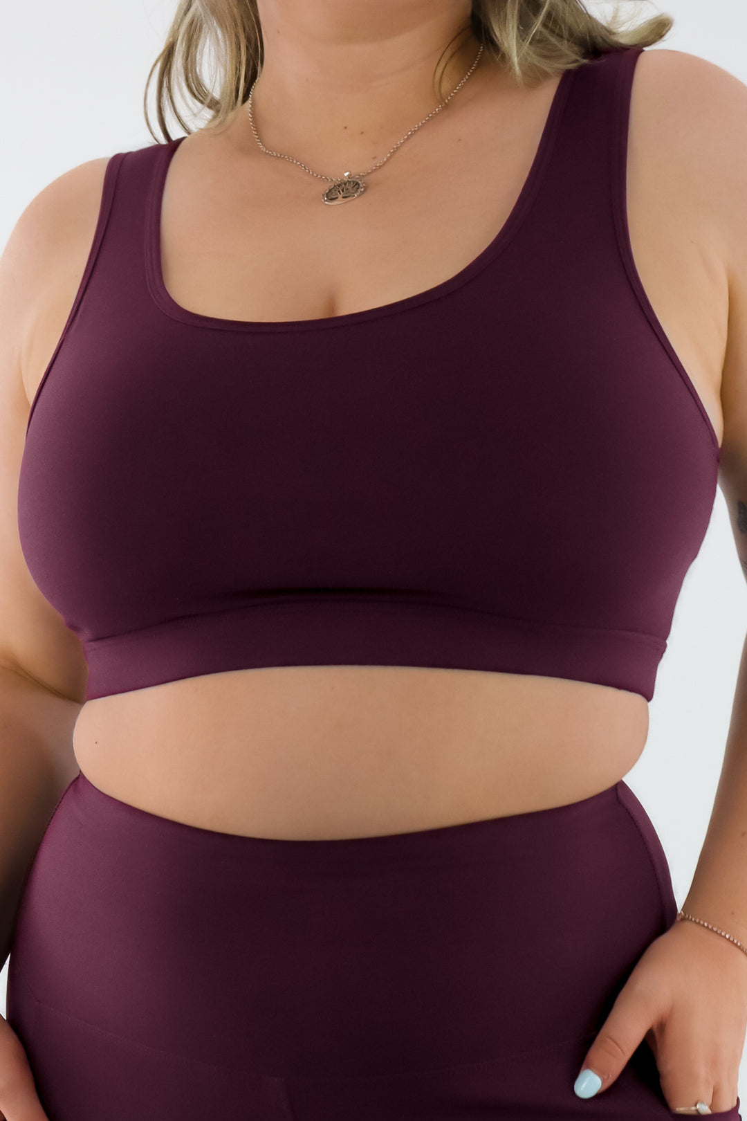 Person wearing a maroon sports bra and leggings set on a white background