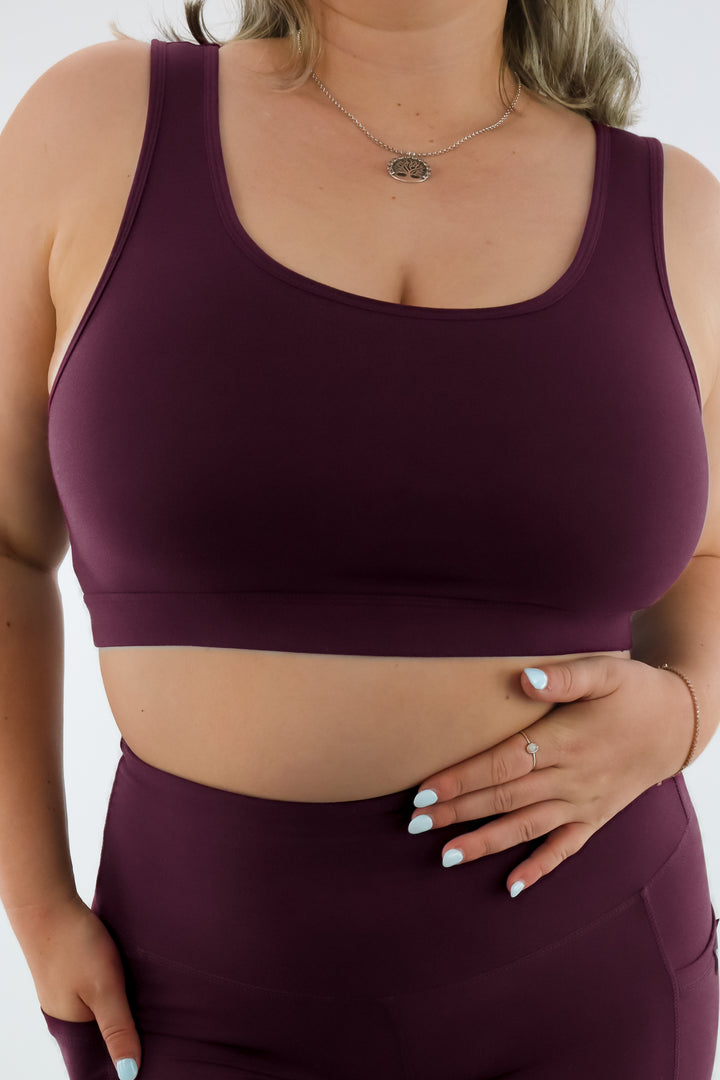 Person wearing a maroon sports bra and leggings on a white background